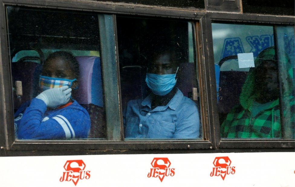 People wearing face masks on board a bus look out the window on 27 April.