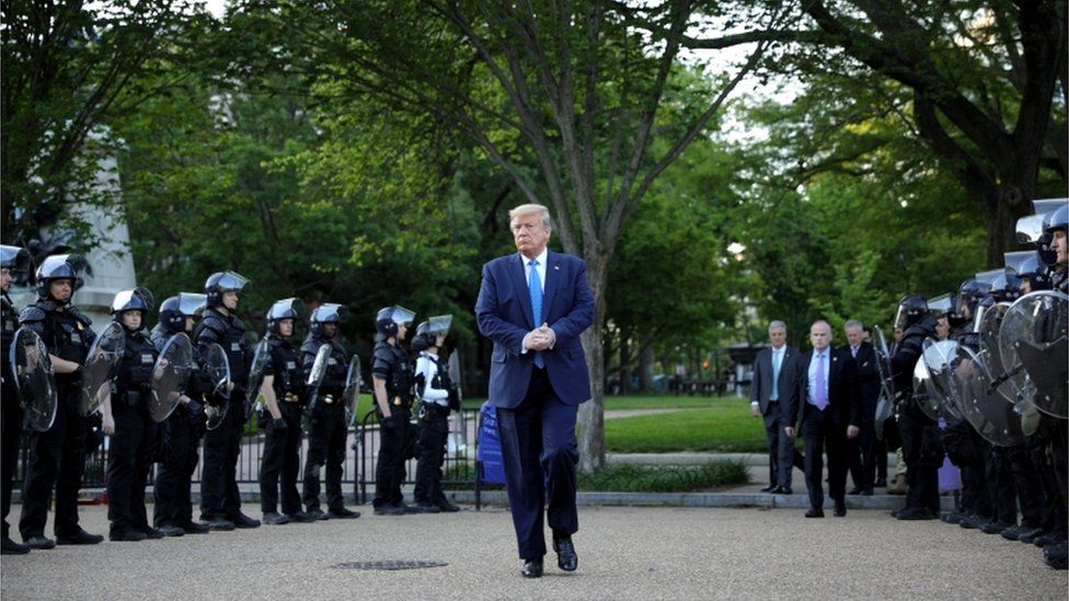 US President Donald Trump walks between lines of riot police on Monday