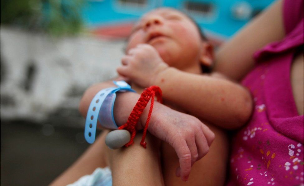 Melissa holds her nine-day old baby Allan, who was born with microcephaly and who wears a good-luck charm, while standing on the roof top of their home in Choluteca, Honduras, 30 July 2016.