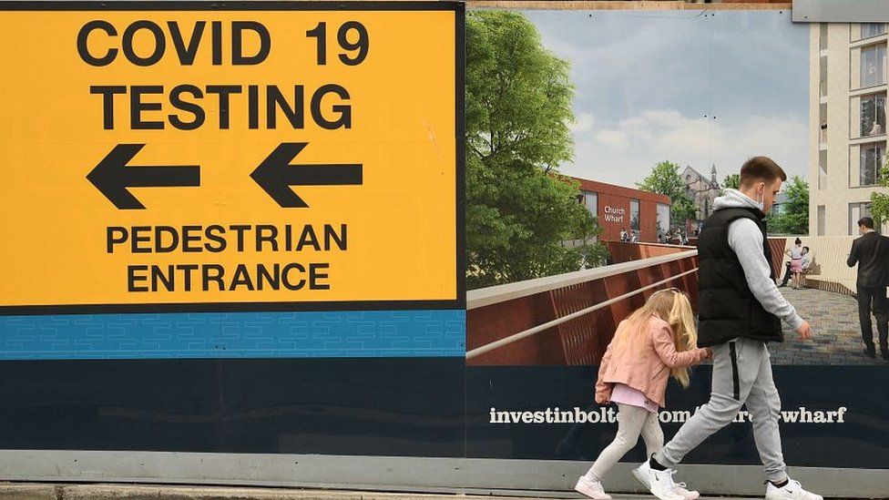 man and girl walking past covid testing sign