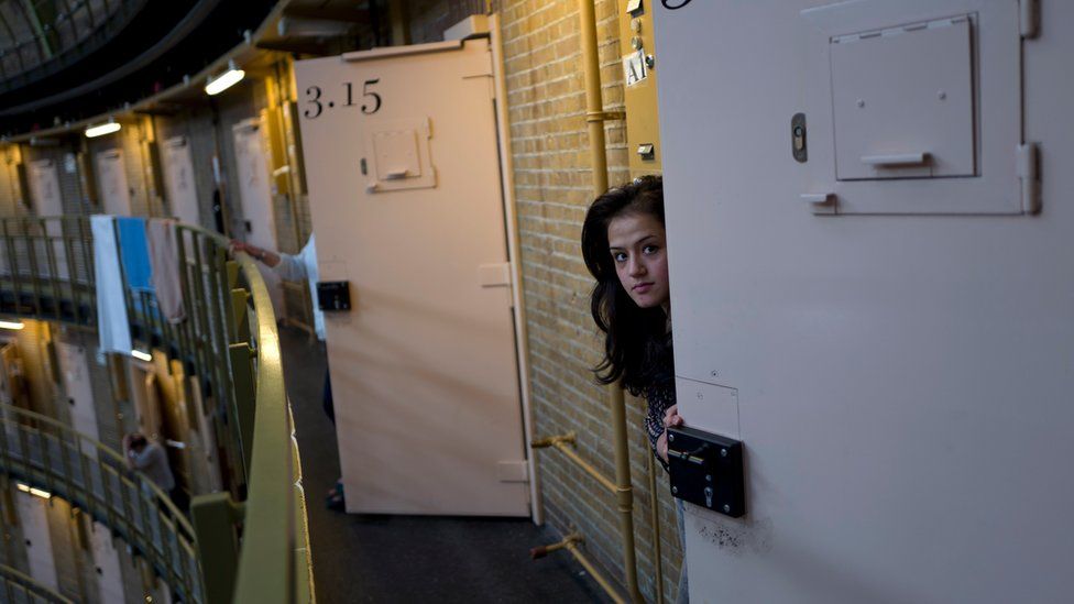 Afghan refugee Shazia Lutfi, 19, peeks through the door of her room at the former prison of De Koepel in Haarlem, Netherlands