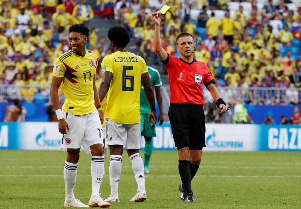 Colombia's Johan Mojica is shown a yellow card by referee Milorad Mazic.