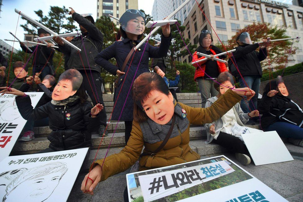 Protesters wearing masks of South Korean President Park Geun-Hye (front) and her confidante Choi Soon-Sil (back) pose as though the latter is a puppet master for the former, at a protest in Seoul on 29 October 2016.