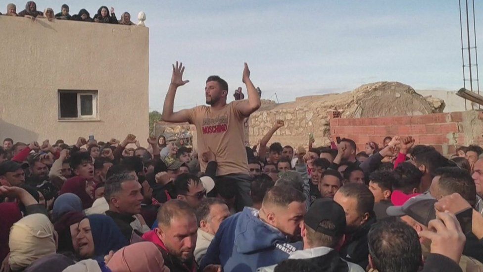 A man holding his hands up in a crowd