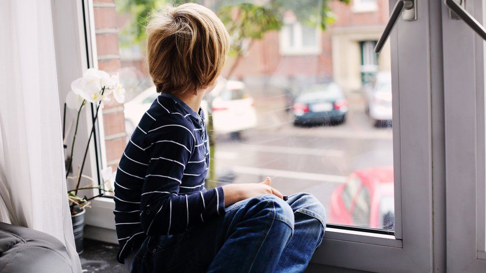 child sitting alone at window