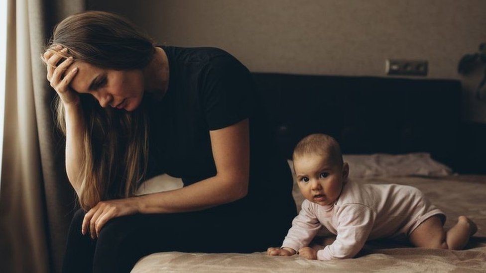 Woman sitting on bed with a baby