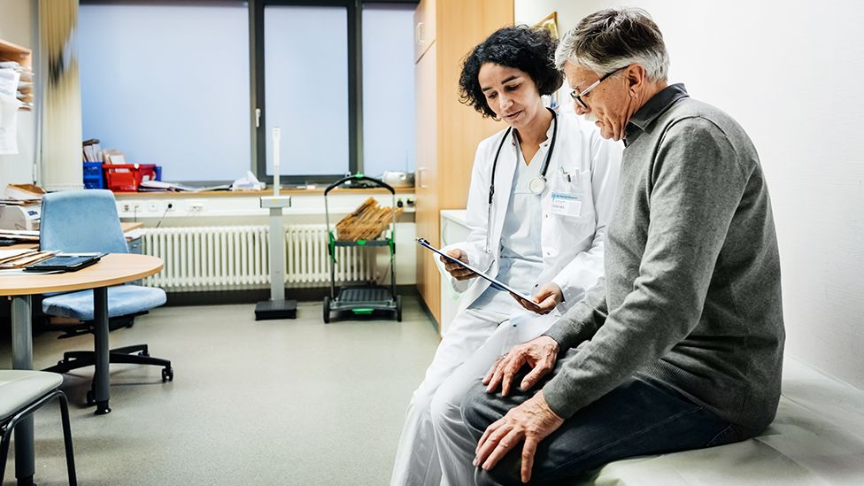 Stock photo showing a doctor and patient in consultation inside doctor's surgery