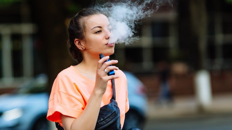 A young woman seen smoking a vape