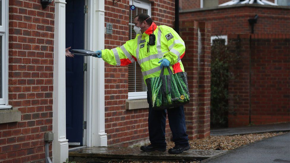 A Community safety patrol officer hands a coronavirus test to a resident in Bramley Green, Hampshire, during a surge testing programme after a case of the South African variant of Covid-19 was identified in the village