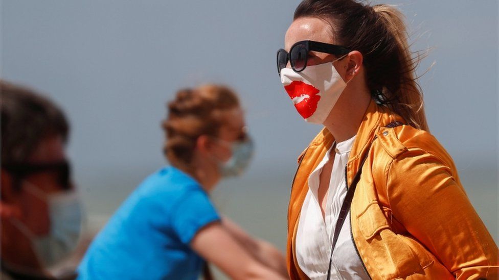 A tourist wearing a protective face mask walks along the beach in Belgium as it was added to the UK's quarantine list