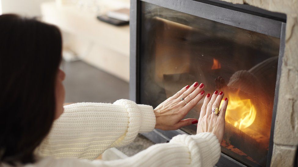 Woman heating hands astatine  fire