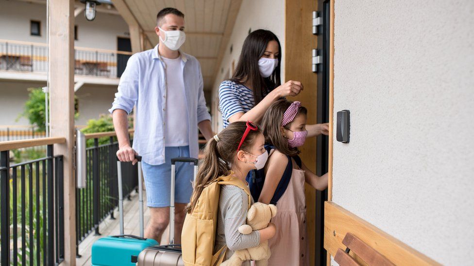 A family wearing face masks checks into a hotel