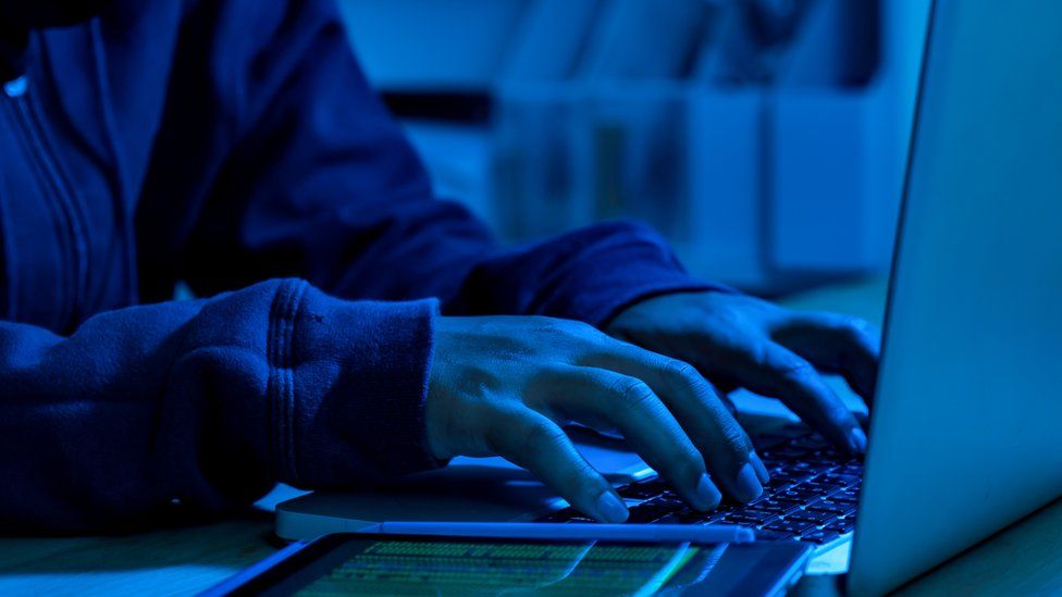 Anonymous person on the computer in blue light