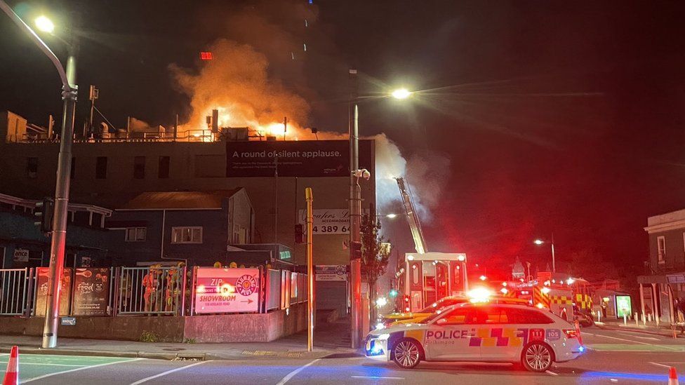 A building on fire with a police car at the scene