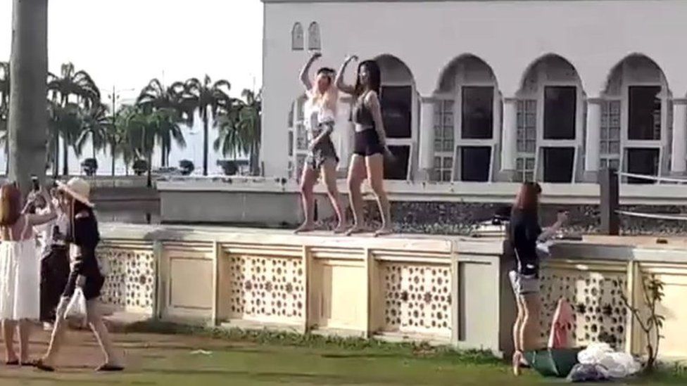 Two women dancing in front of the Kota Kinabalu City Mosque, Malaysia