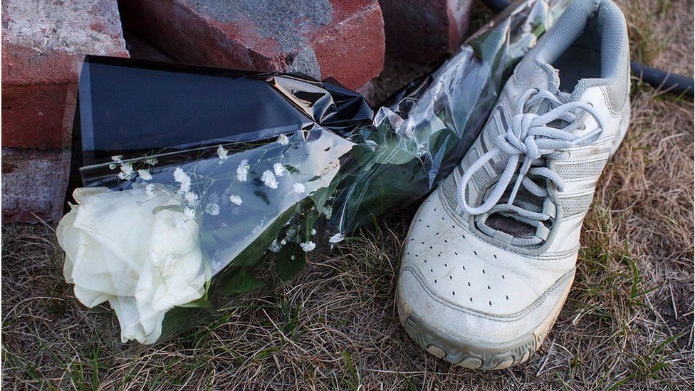 A running shoe and white rose at a memorial