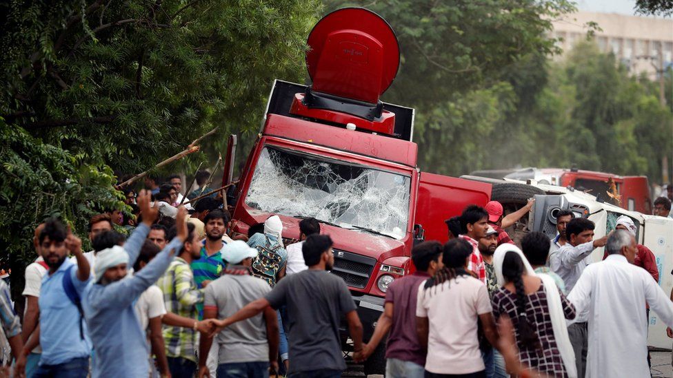 Участники беспорядков разбили грузовики с телевизором во время беспорядков в Панчкуле, Индия, 25 августа 2017 г.