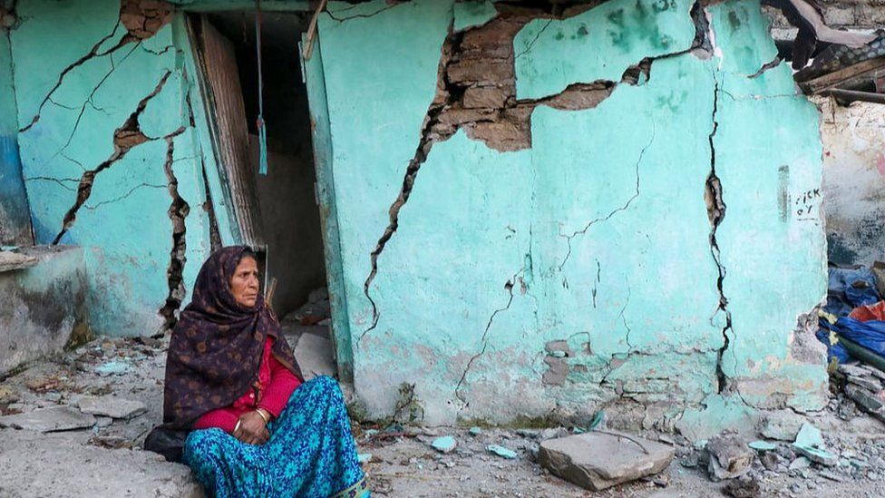 A woman sits beside a cracked wall of her house in Joshimath, 10 Jan 23