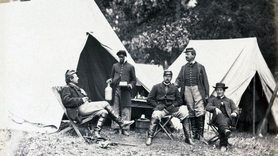 A black orderly serves drinks to Union officers during the Civil War