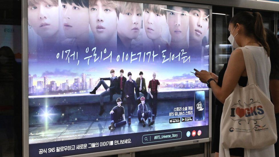 A woman walks past a commercial poster showing K-pop group BTS members at a subway station in Seoul on September 1, 2020. BTS has become the first all-South Korean act to rule the top US singles chart