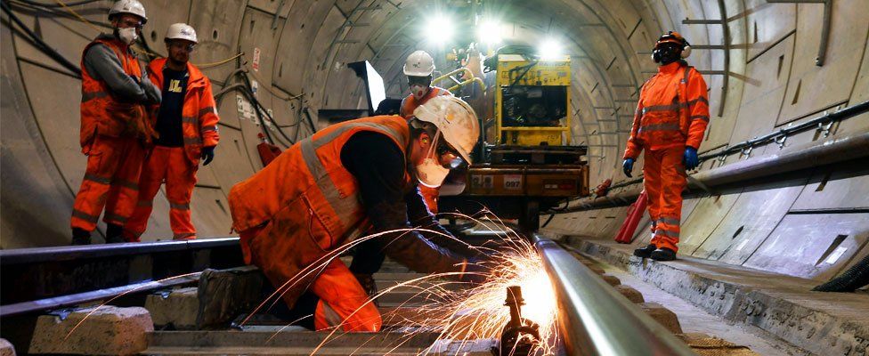 Construction workers work on a section of train track inside a Crossrail tunnel, beneath Stepney in east London in 2016