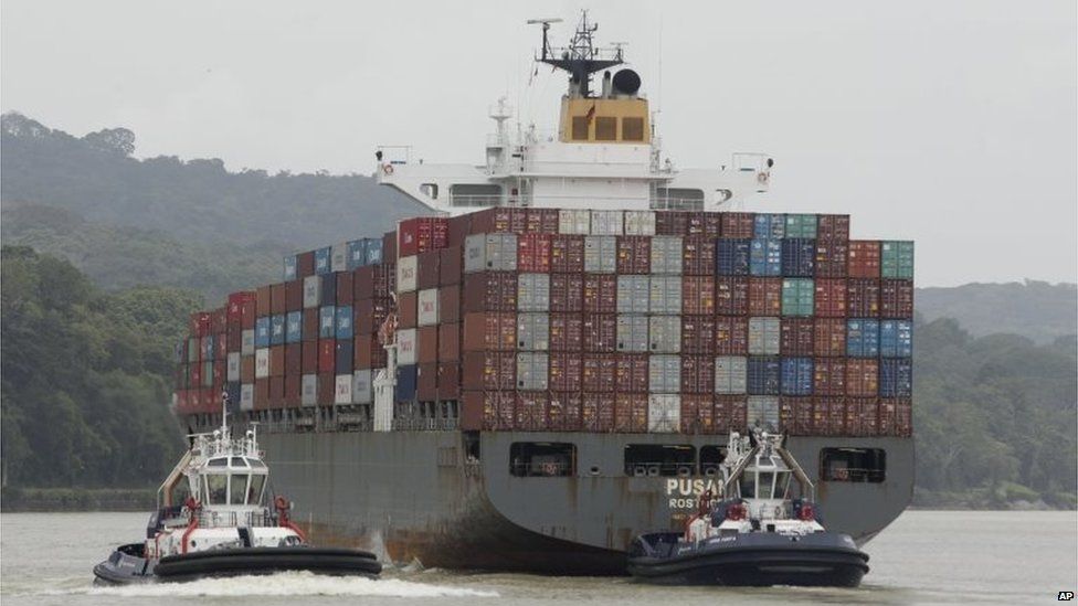 Tugboats guide a cargo ship on Panama Canal waters in Gamboa on 8 August 2015.