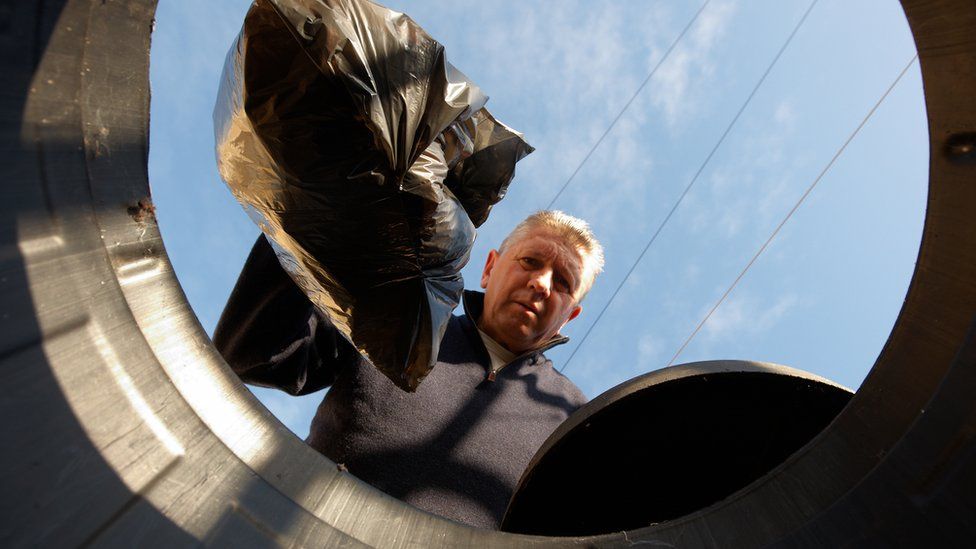 man putting rubbish in bin