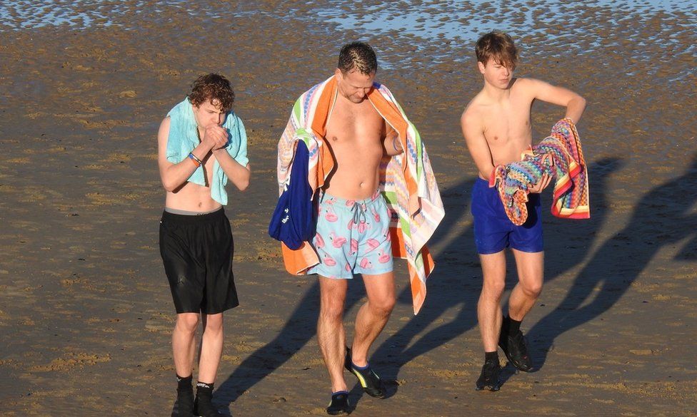 Three males looking cold having been for a swim