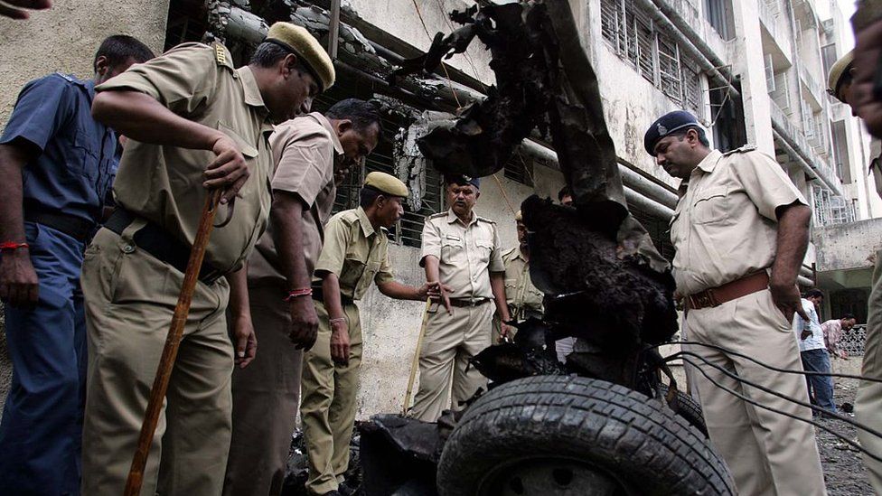 Серийные взрывы в Ахмадабаде. Полицейские осматривают место, где произошли два взрыва в Гражданской больнице. Обгоревшие остатки автомобилей и мотоциклов оцепили для досмотра - HT Фото Виджаянанда Гупта 27.07.2008
