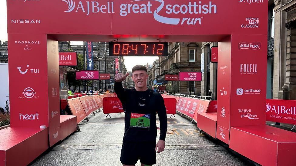 John Connolly stands in front of the finish line the Great Scottish Run.