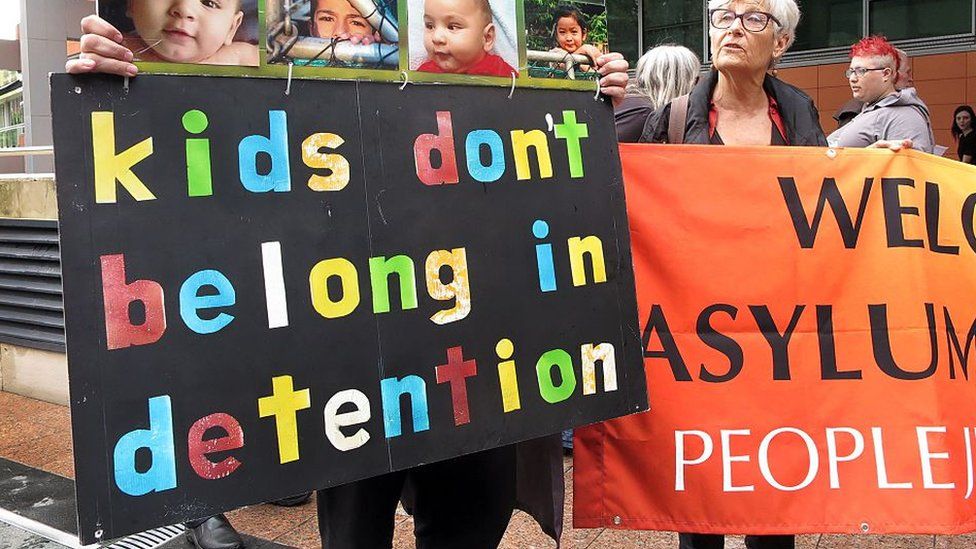 A man holds a sign saying kids don't belong in detention