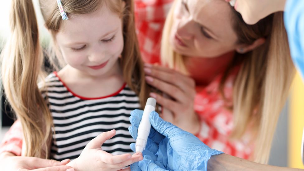 A nurse takes a glucose test from a child