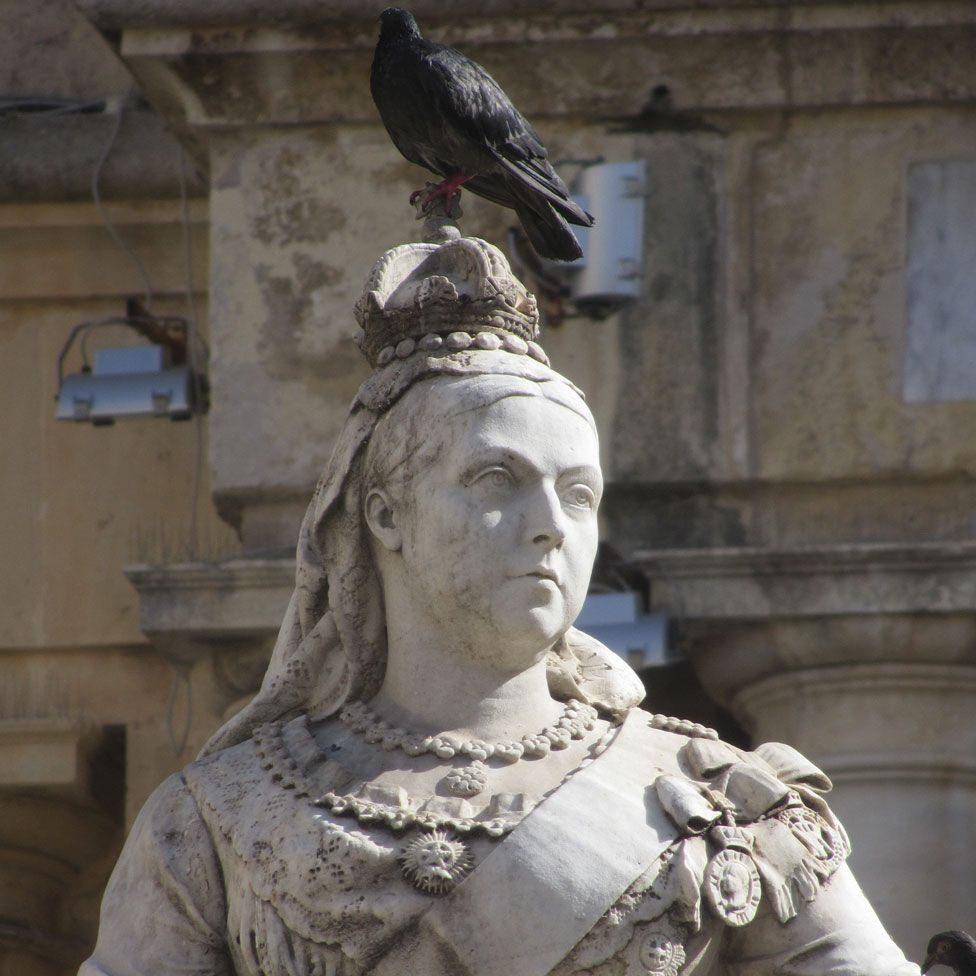 A statue of Queen Victoria in Malta with a pigeon on top of her head