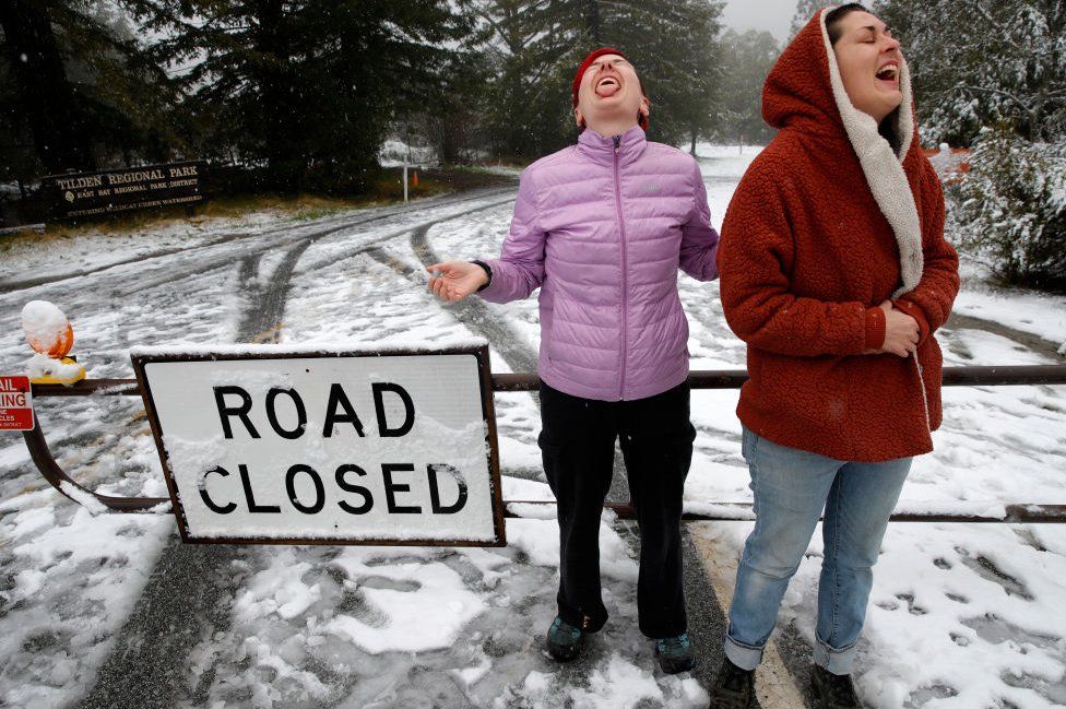 Woman try to catch snowflakes on their tongues in Berkely