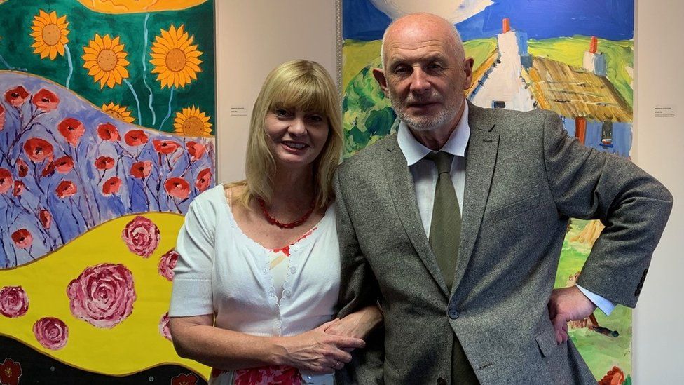 Artists Angela Patchett and Michael Starkey in front of two of the paintings