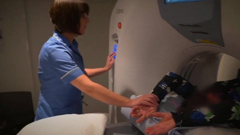 Nurse holds patient's arm in scanning machine
