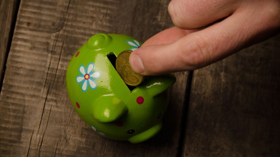 Hand putting money in piggy bank