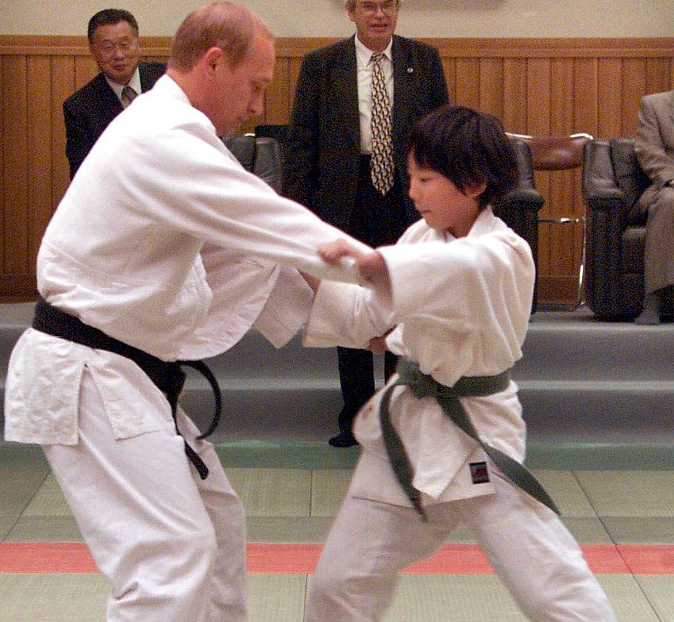 Russian President Vladimir Putin (L) in judo outfit fights against 10-year-old Japanese schoolgirl Natsumi Gomi as he visits a Tokyo judo training center Kodokan hall 05 September 2000. Putin, who has a black belt in the sport, was thrown over her shoulder onto the mat.