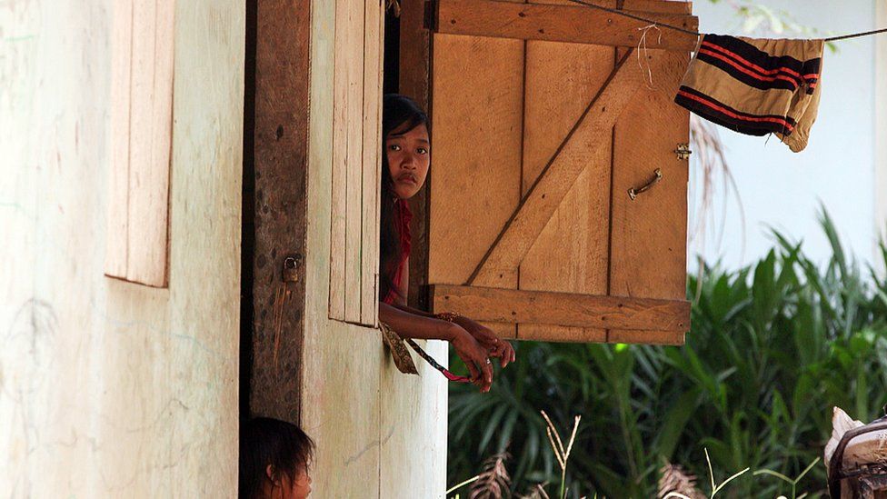 A girl looking out of the window on the Orang Rimba estate
