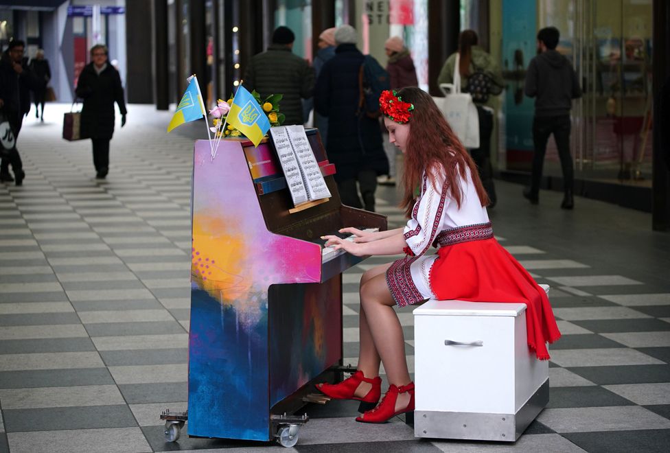 Die ukrainische Teenagerin Alisa Bushuieva, die im Februar letzten Jahres gezwungen war, mit ihrer Mutter Svitlana aus ihrem Land zu fliehen, spielt nach einer Schweigeminute in der Peter's Lane in Liverpool ONE Klavier für die Menge.