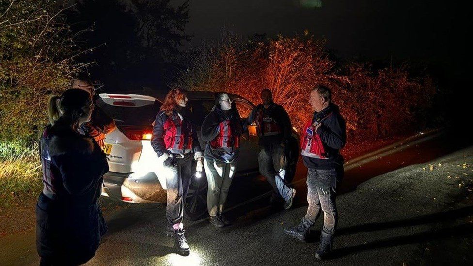 Five suicide prevention volunteers outside in the dark near a car