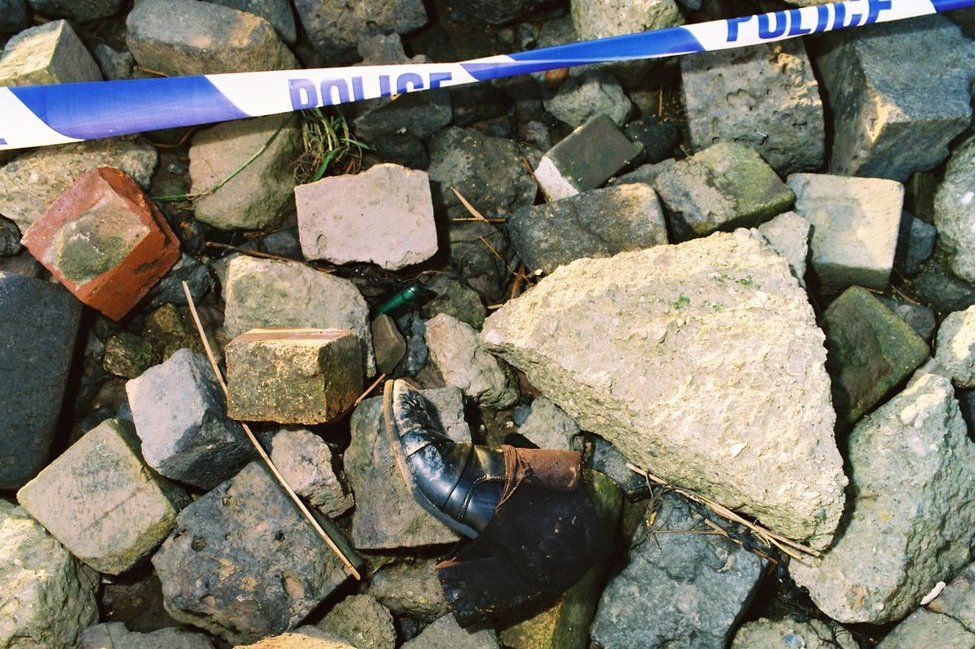 Boot on rocks with police tape next to it