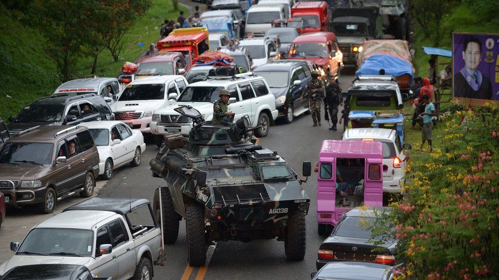 An armoured personnel carrier moves amongst stuck vehicles of residents fleeing Marawi City, in the southern island of Mindanao