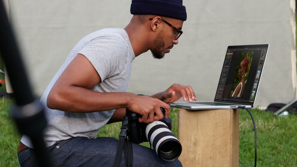 A photographer using a MacBook
