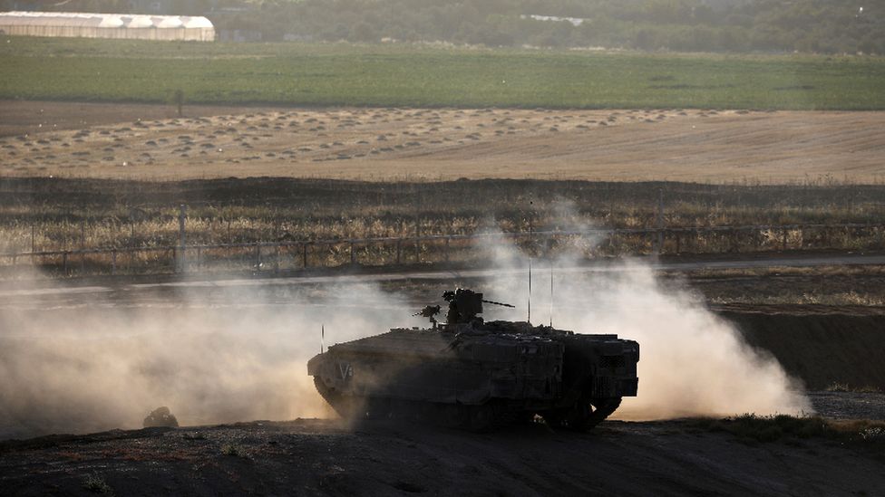 An Israeli armoured personnel carrier manoeuvres on the Israeli side of the border fence between Israel and the Gaza Strip