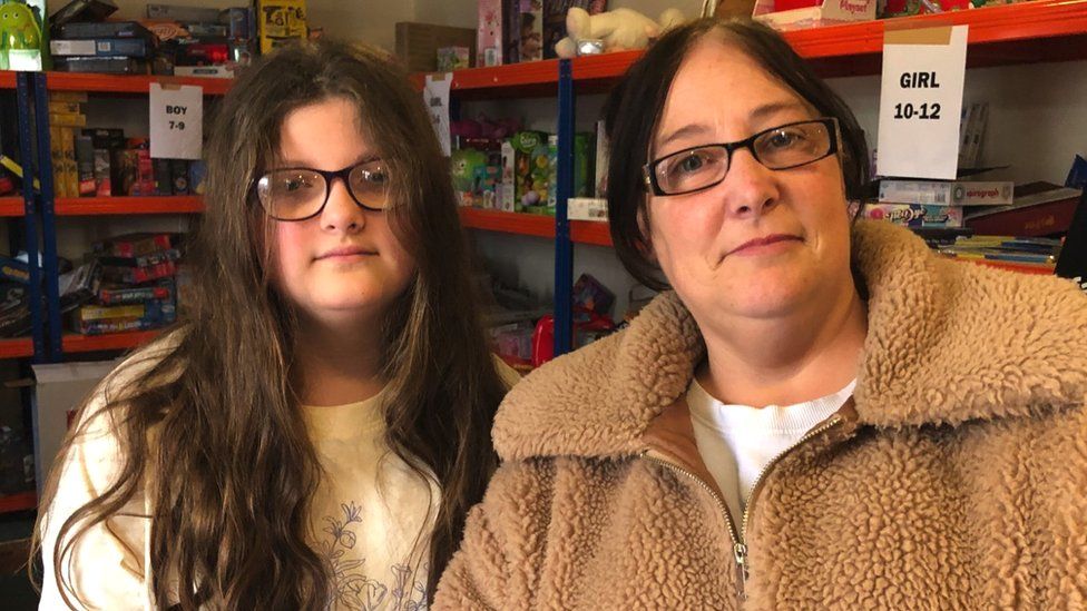 Ava (left) has long dark hair and glasses. She is smiling. Next to her on the right is her mother, Chantal. She is also smiling.
