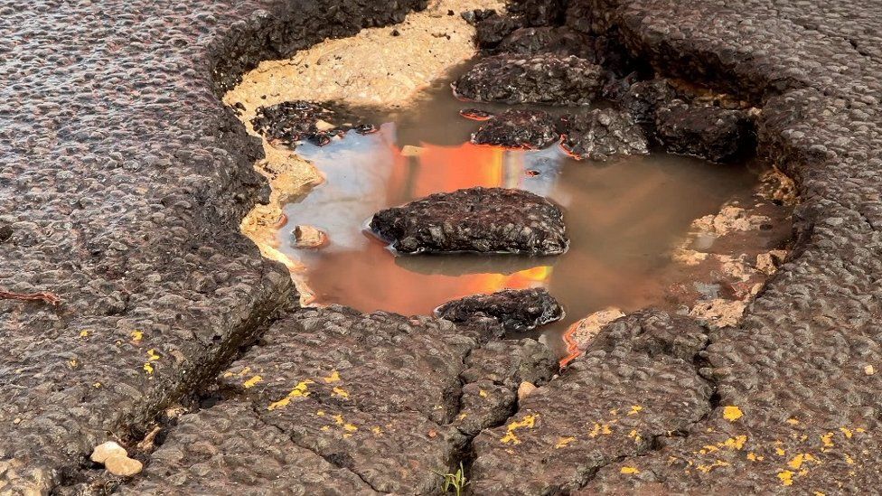 A close-up of a pothole with water in it.