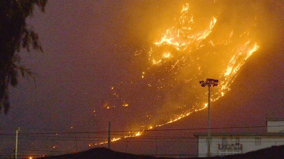 Пламя поднимается, когда лесной пожар горит на холмах недалеко от Палермо