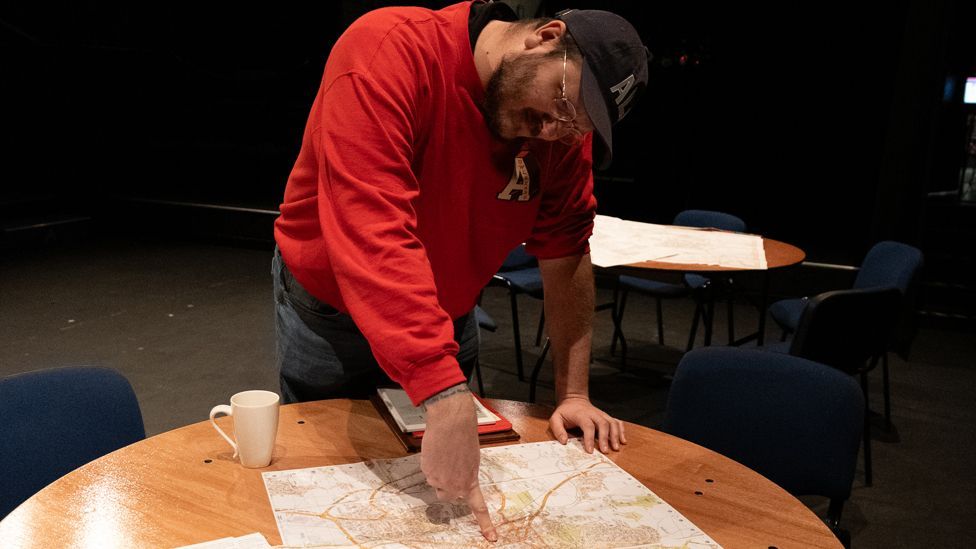 Alex Levene pointing to a map