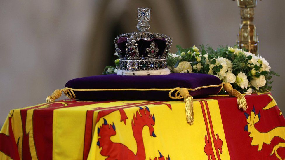 The coffin of Queen Elizabeth II, draped in the Royal Standard with the Imperial State Crown and the Sovereign's orb and sceptre, lying in state on the catafalque in Westminster Hall, at the Palace of Westminster, London. Picture date: Wednesday September 14, 2022.